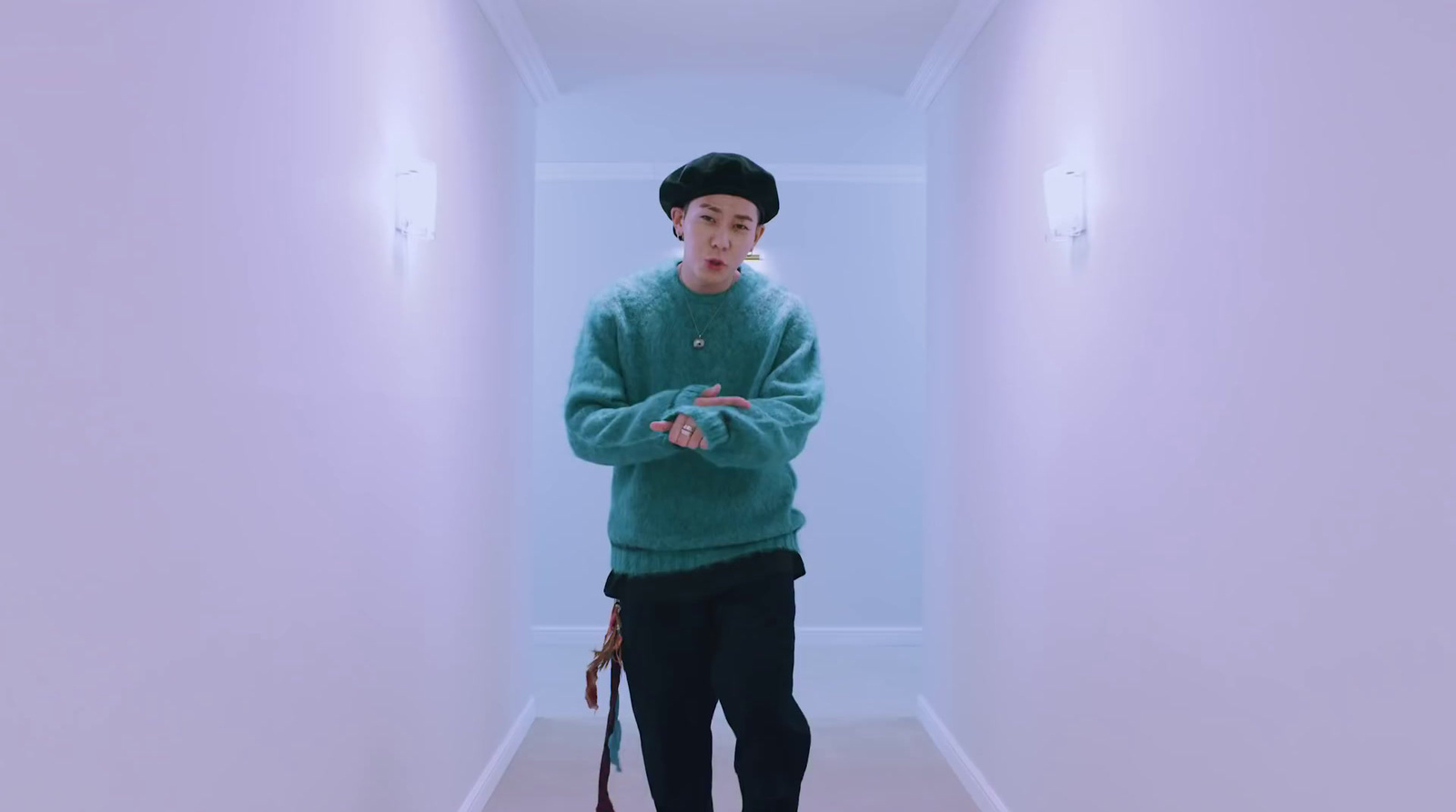 a man in a green sweater is standing in a hallway