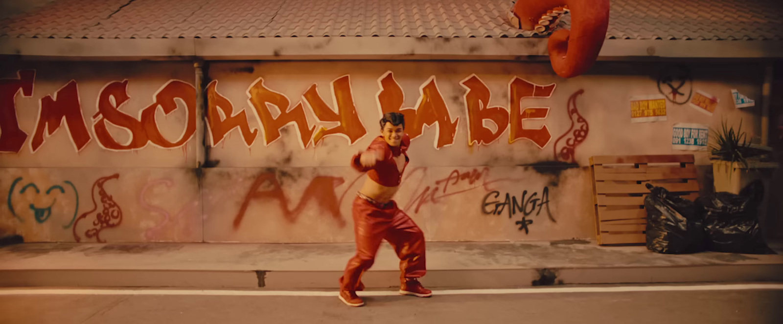 a woman in a red outfit is standing in front of a wall with graffiti