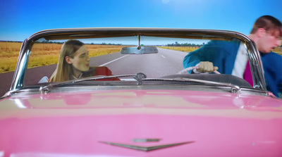 a man driving a pink car next to a woman