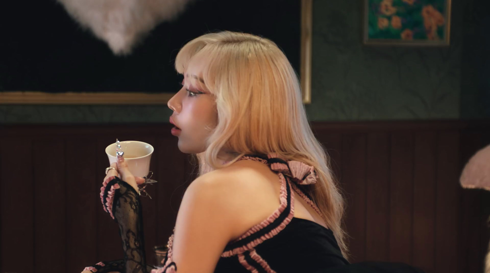 a woman in a black dress holding a cup of coffee