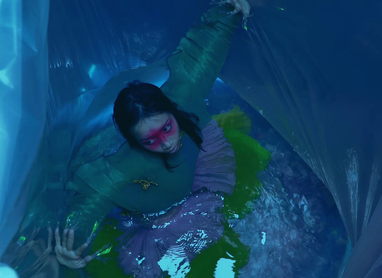 a woman in a blue and green costume floating in a pool