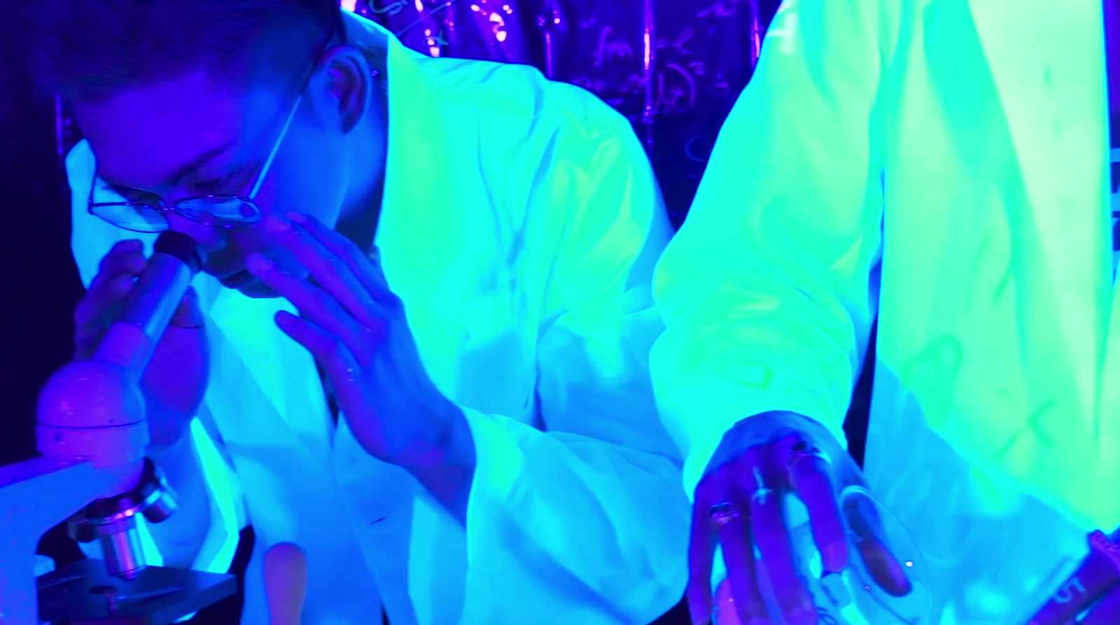 a man in a lab coat looking through a microscope