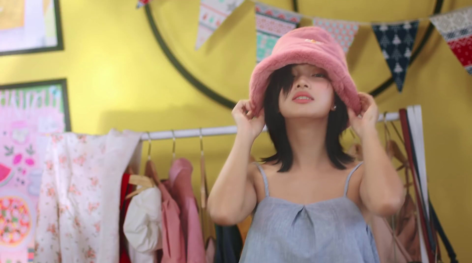 a woman wearing a pink hat standing in front of a yellow wall