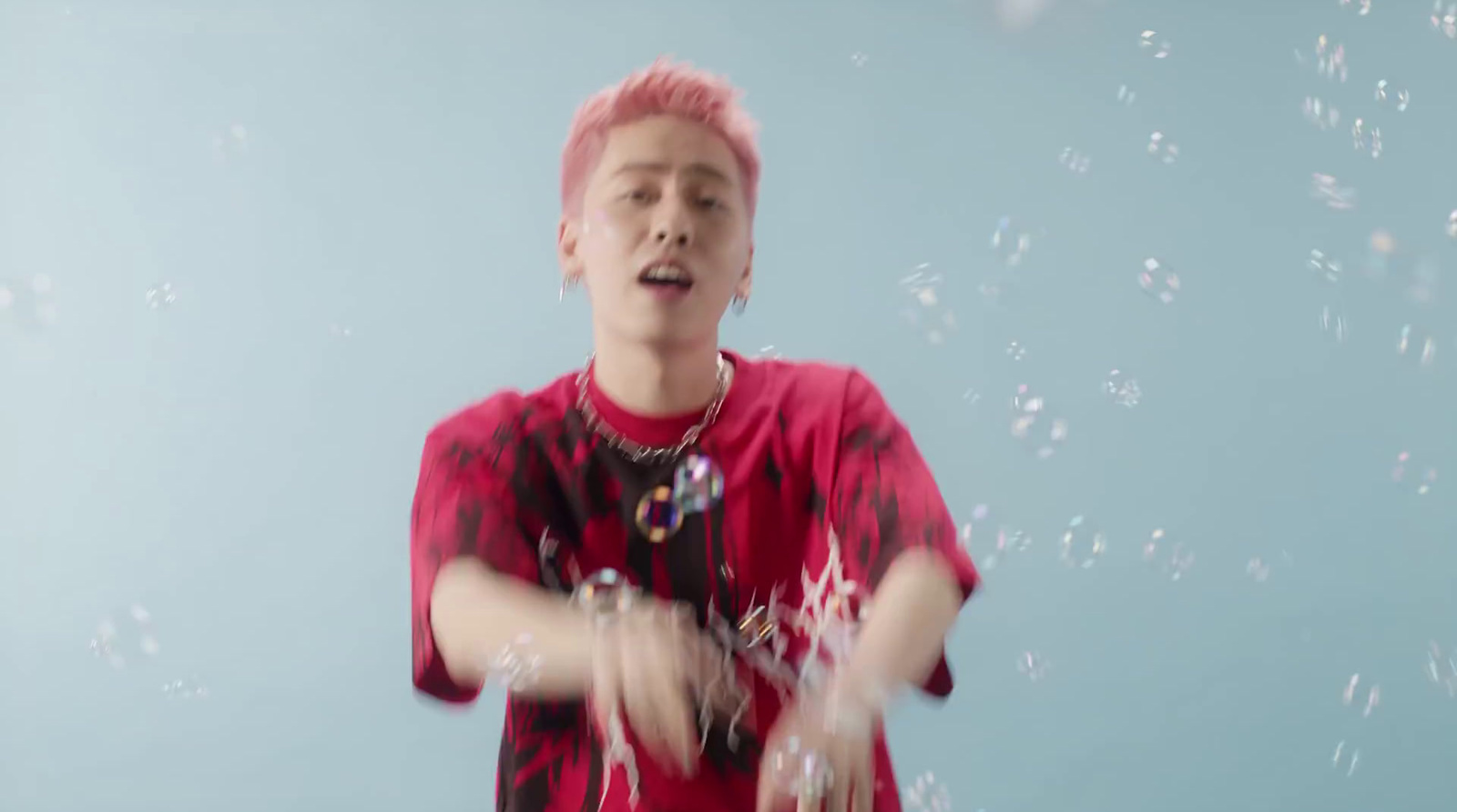 a boy with pink hair blowing bubbles in the air