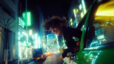 a man leaning out of a green car on a city street