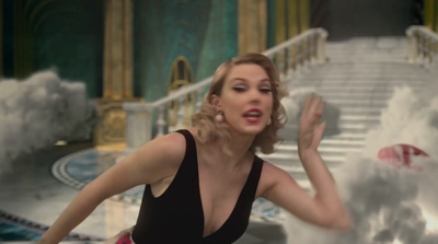 a woman in a black dress standing in front of a staircase