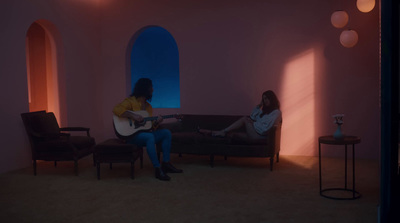 two women sitting on a couch playing guitars