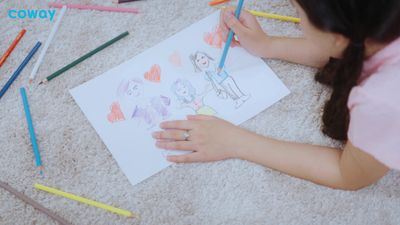 a young girl is drawing with colored pencils