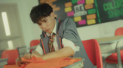 a young man sitting at a desk writing on a piece of paper