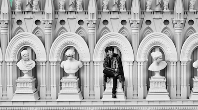 a person sitting on a ledge in front of a building