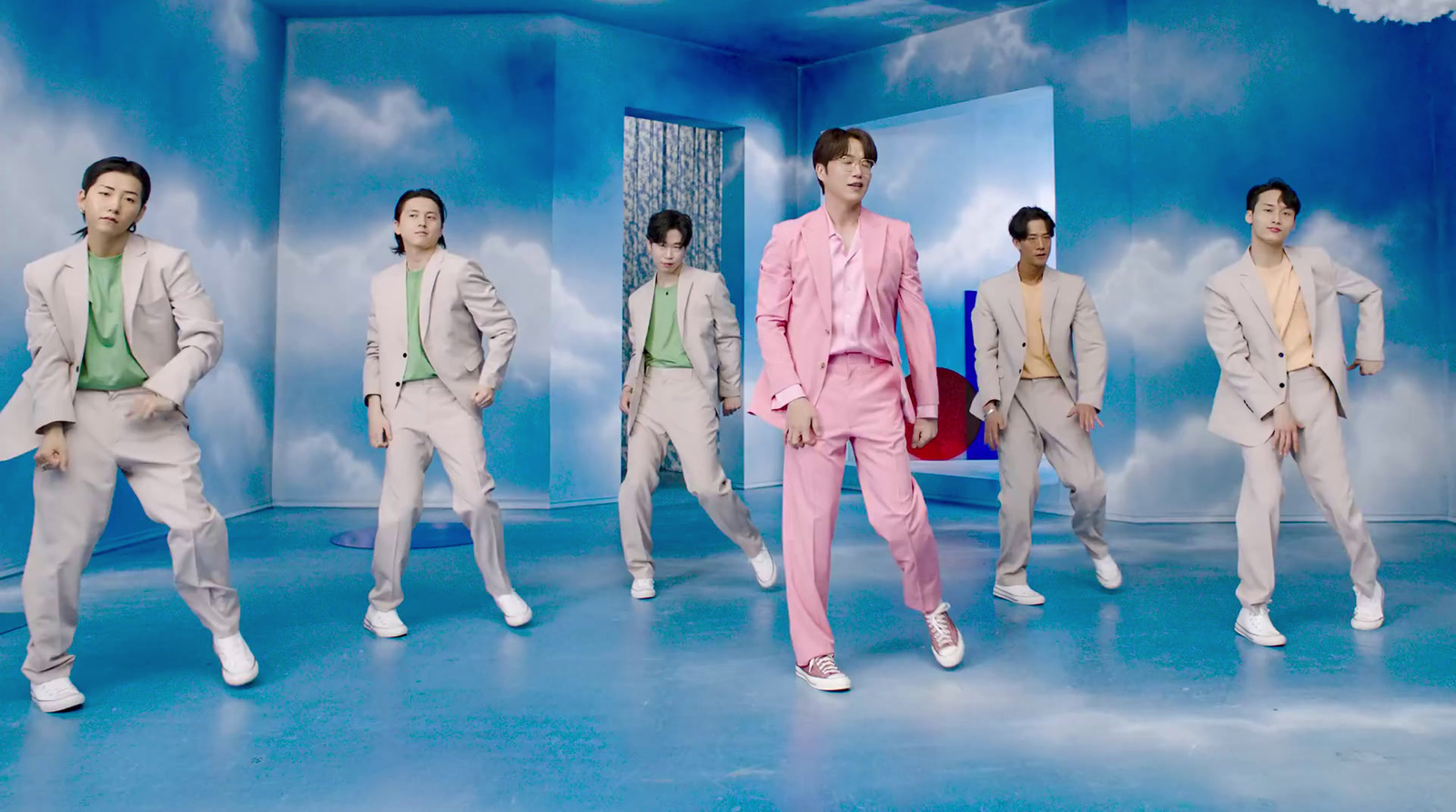 a man in a pink suit standing in front of a group of men