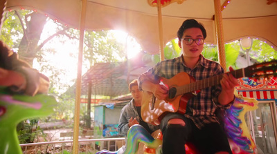 a man sitting on a carousel playing a guitar