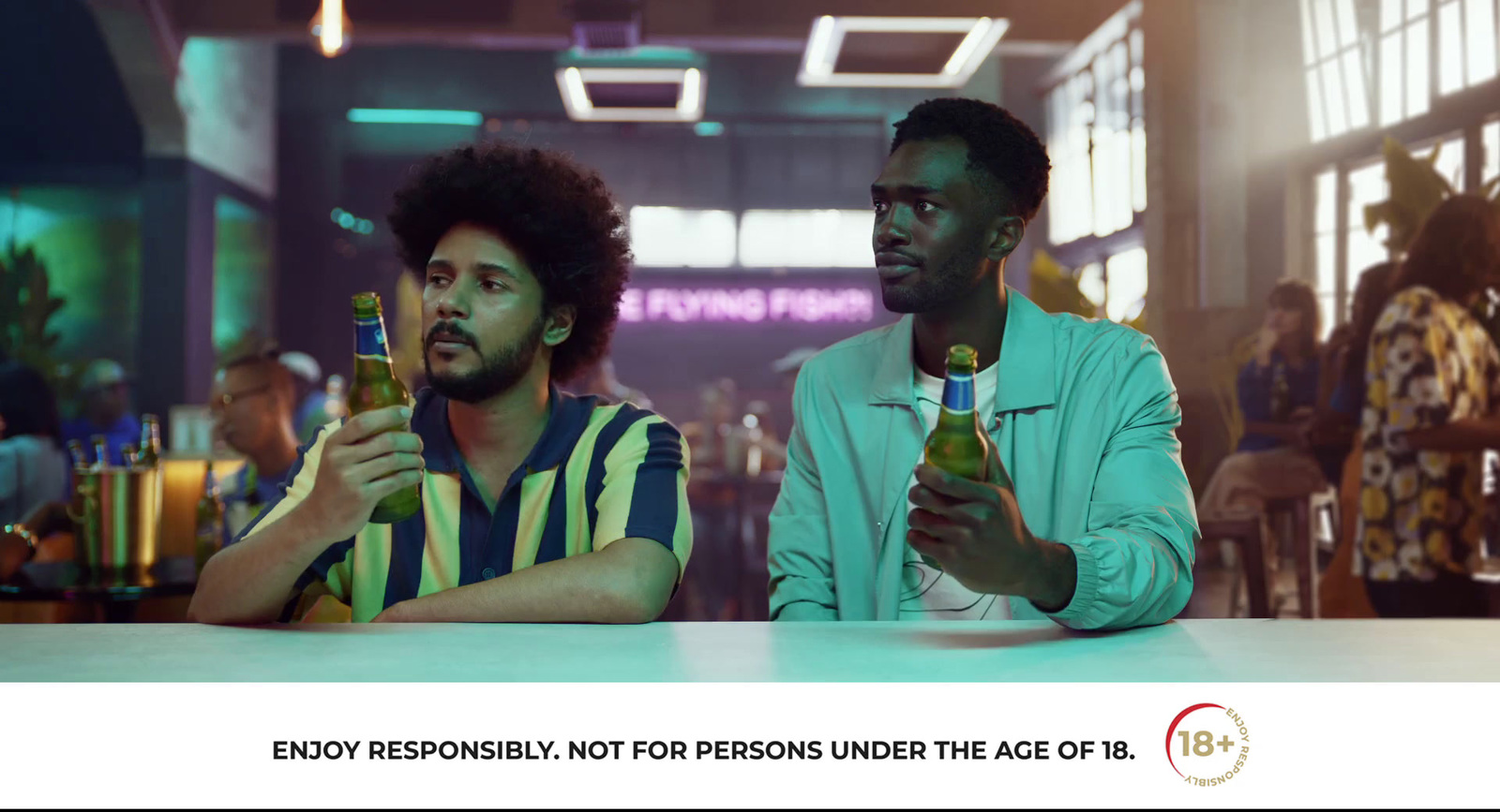 two men sitting at a table with bottles of beer