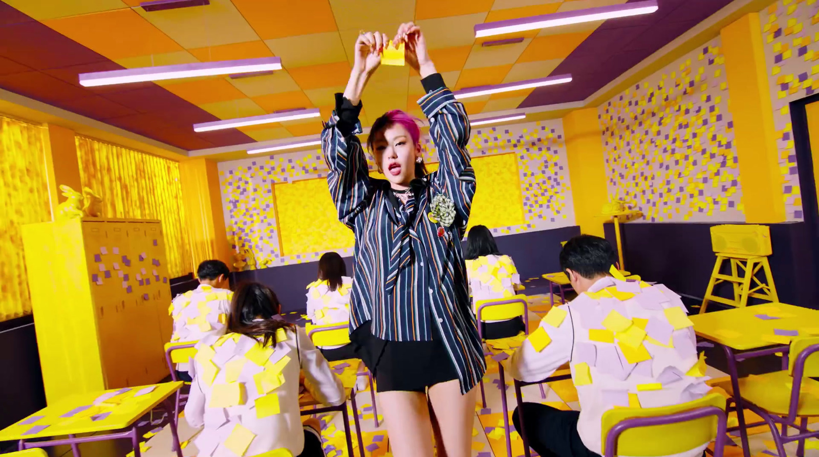 a woman with red hair standing in a room with yellow chairs