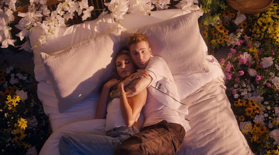 a man and a woman laying in a bed of flowers