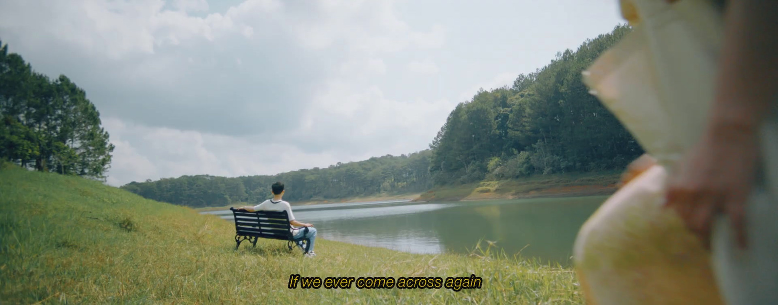 a man sitting on a bench next to a lake