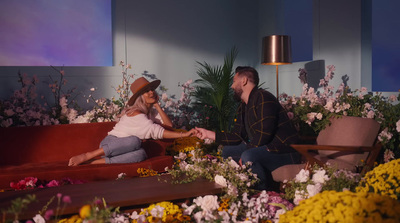 a man and a woman sitting on a couch in a room full of flowers