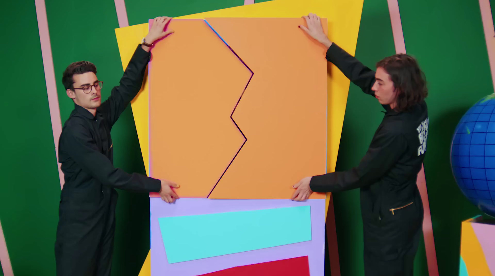 two people standing next to each other holding a large piece of art