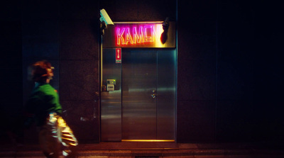 a person walking past a neon sign on a building