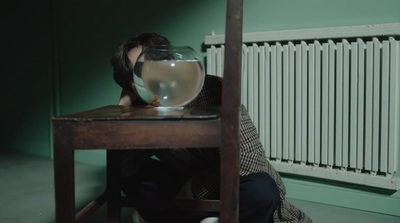 a person sitting at a table with a fish bowl in front of them