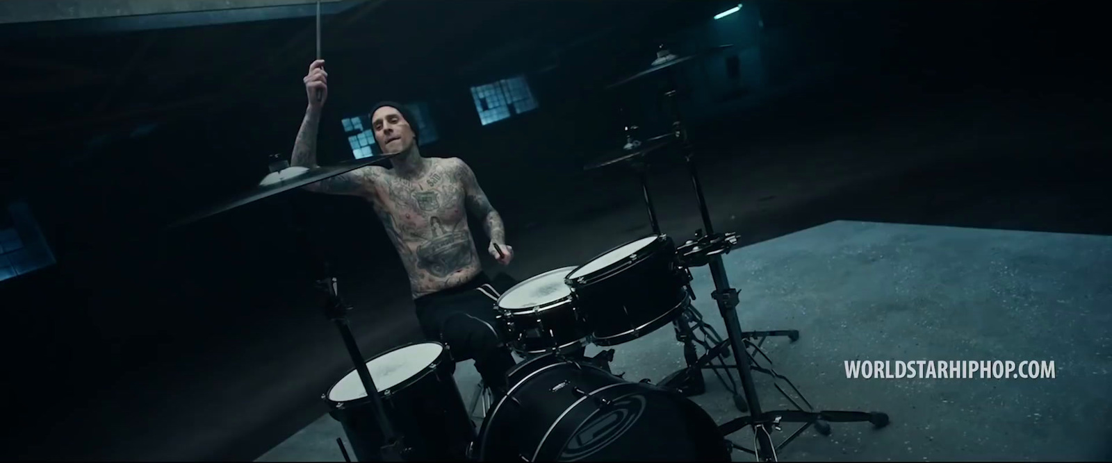 a man with tattoos playing drums in a dark room