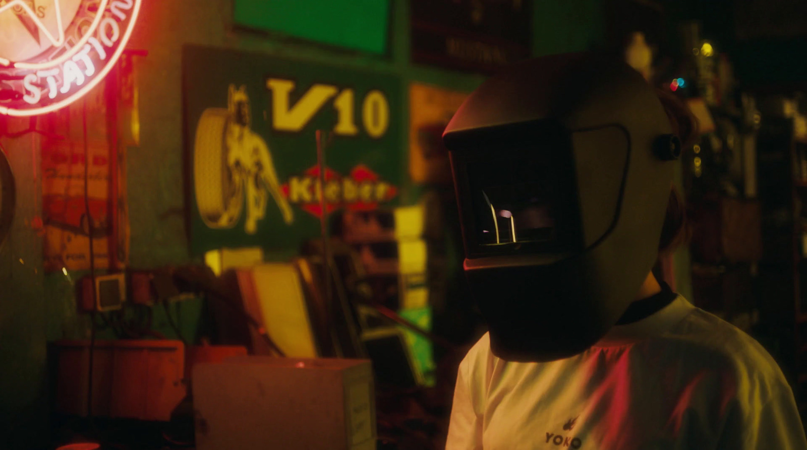 a man wearing a gas mask standing in front of a neon sign