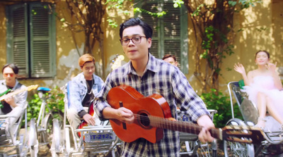 a man playing a guitar in front of a group of people