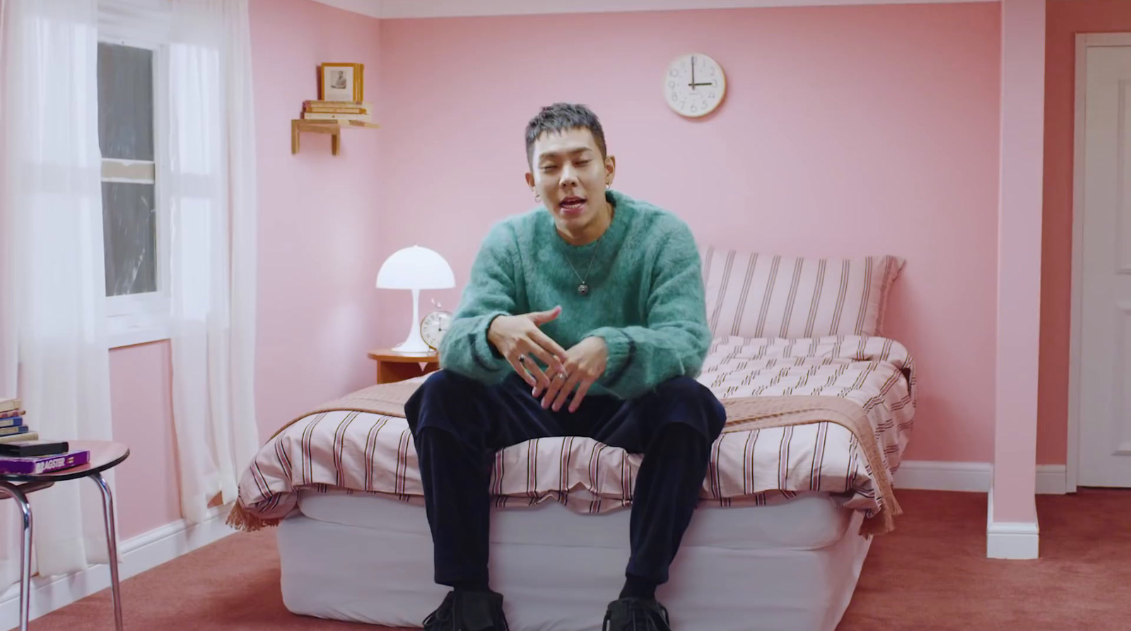 a man sitting on a bed in a pink room