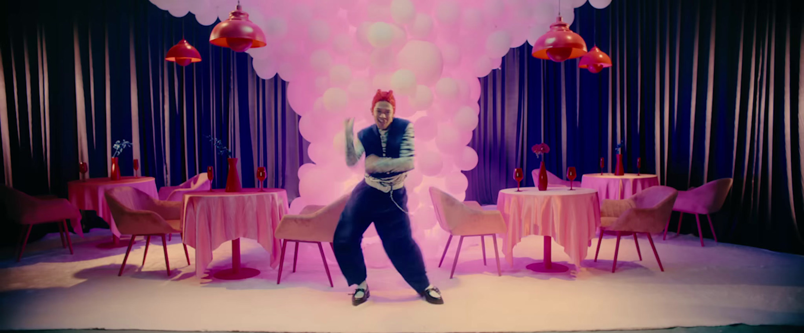 a man standing in front of a table with pink chairs