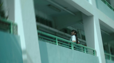 a woman standing on a balcony next to a building