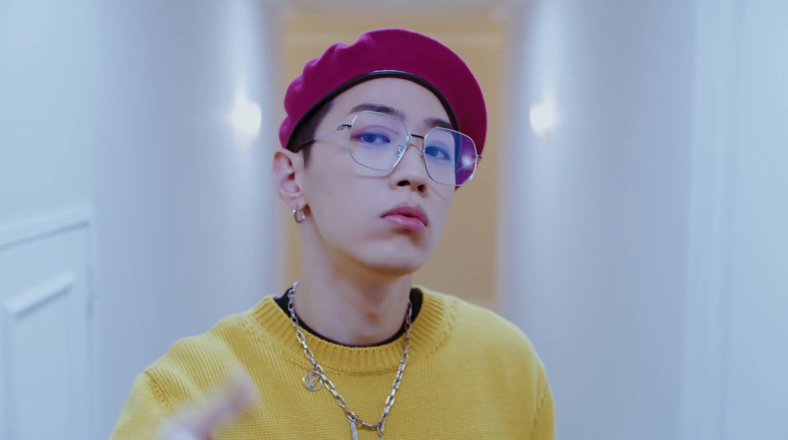 a young man wearing glasses and a yellow sweater