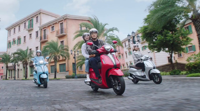 a man and a woman riding on the back of a red scooter