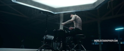 a shirtless man playing drums in a dark room