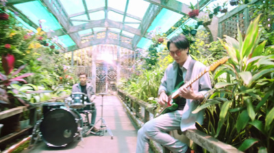 a man playing a guitar in a greenhouse