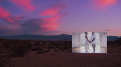 a person standing in front of a large screen in the middle of a desert