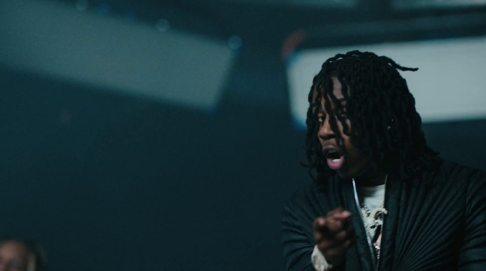 a man with dreadlocks standing in a dark room