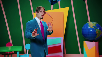 a man in a blue suit is standing in front of a colorful wall