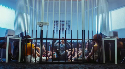 a group of people sitting in a room behind a fence