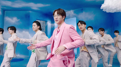 a man in a pink suit standing in front of a group of other men