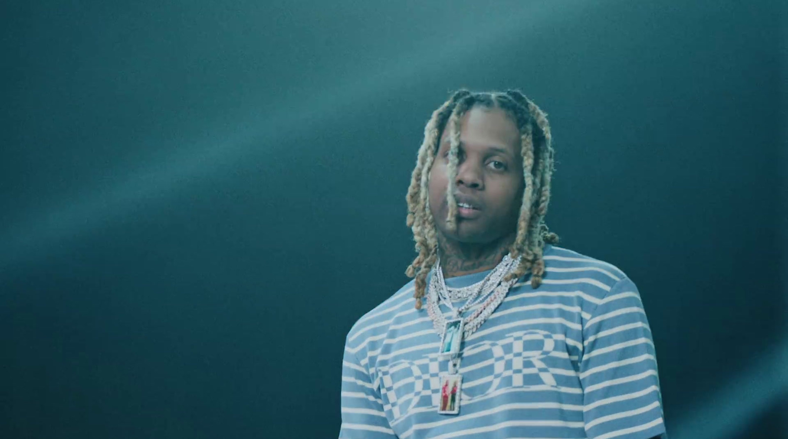 a man with dreadlocks standing in front of a black background