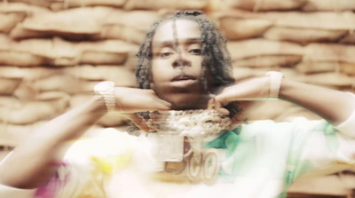 a man with dreadlocks standing in front of a wall