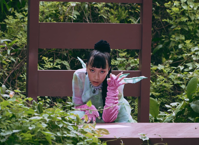 a young girl sitting on a bench in a garden