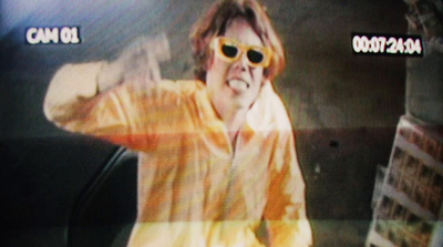 a man in a yellow jacket and sunglasses on a television screen