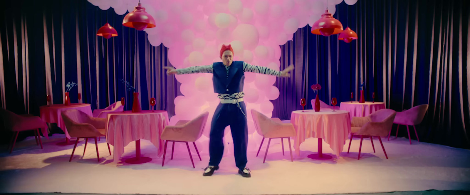 a man standing in front of a table with pink chairs