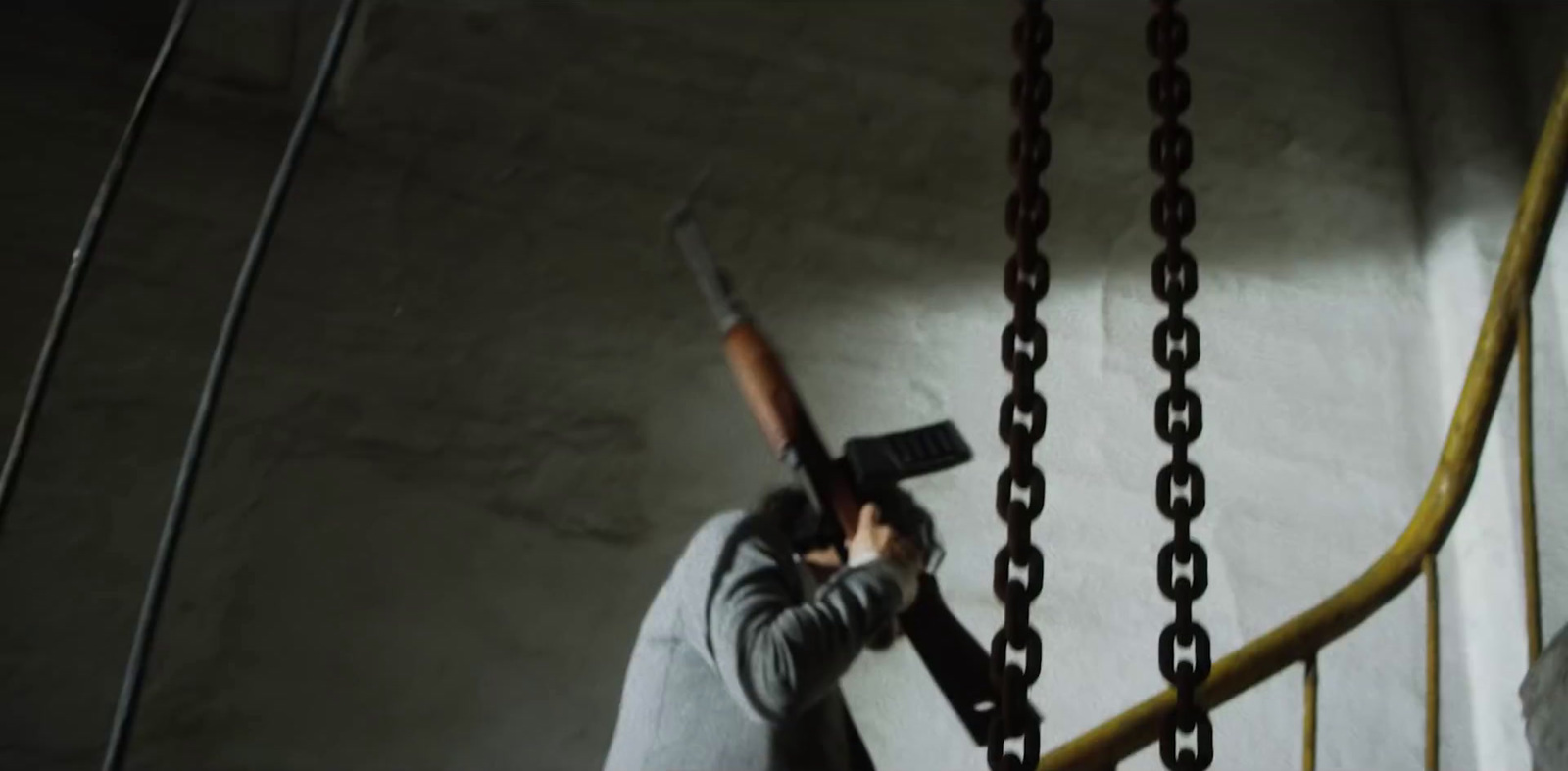 a man holding a gun while standing on a stair case