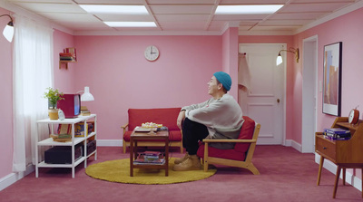 a woman sitting on a red couch in a pink room