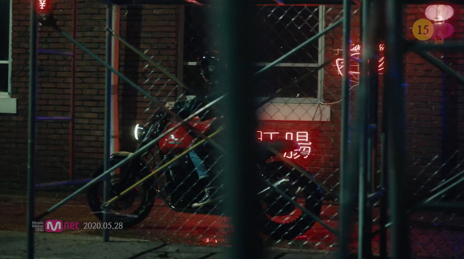 a motorcycle parked in front of a building behind a chain link fence