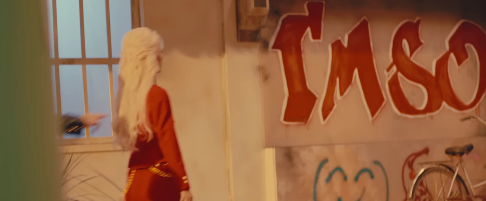 a woman in a red dress standing in front of a graffiti covered wall