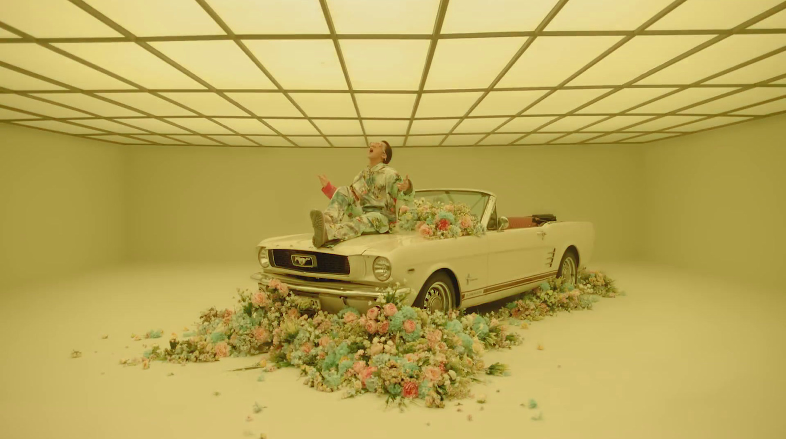 a man sitting on top of a car surrounded by flowers