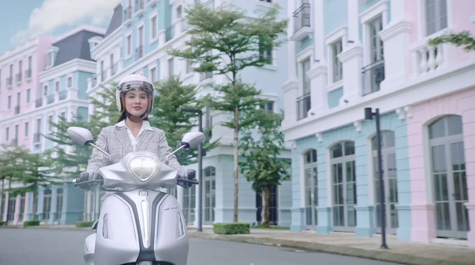 a woman riding a white scooter down a street